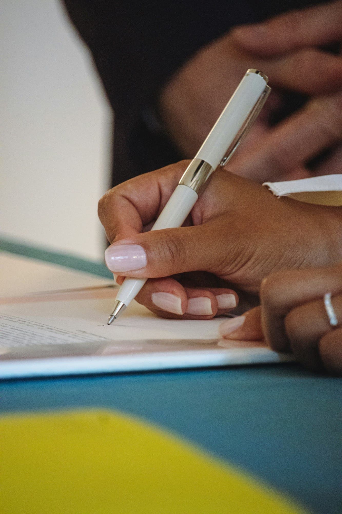 Hands signing a financial document, suggesting diaspora homeownership.